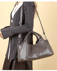 Detail of grey lychee pattern handbag with braided handle shown on model outfit
