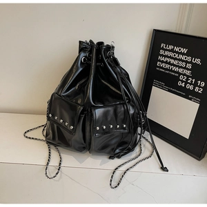Detail of black glossy leather bucket bag with silver studs and chain shoulder strap