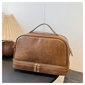 Close-up of brown textured leather cosmetic bag with double-layer design and gold zippers