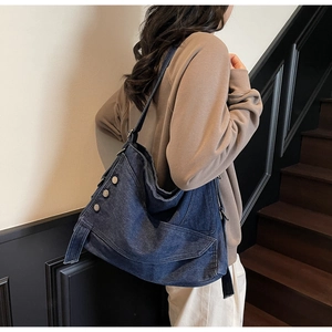 Detailed side view showing silver buttons and pleated denim texture on the blue hobo bag