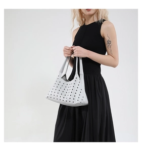 Close-up of metallic silver underarm bag with hollow-out rivet eyelets and modern texture