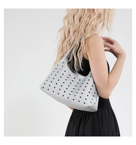 Detail der silbernen Metallic-Schultertasche mit Metallösen und strukturiertem Leder