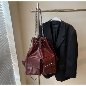 Detail of burgundy leather bucket bag with silver studs and chain strap on metal hanger