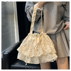 Detalle del bolso tote de lona crema con volantes florales y cierre de cordón ajustable