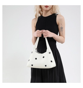 Detailed close-up of white rivet hollowed shoulder bag with silver eyelets and smooth leather