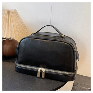 Detailed macro view of the black dual-layer PU leather toiletry bag with golden hardware