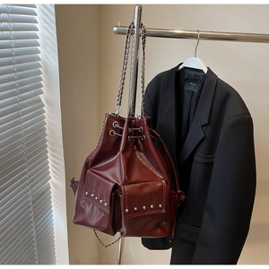 Detailed close-up of dark red bucket bag with silver studs and chain on a hanger