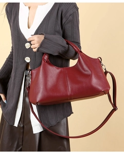 Macro shot of burgundy pebble grain leather texture and handle stitching on a tote bag