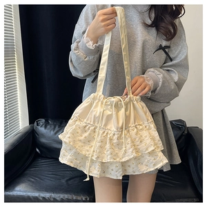 Detalle del bolso tote floral crema con bordes de volantes y cierre de cordón ajustable