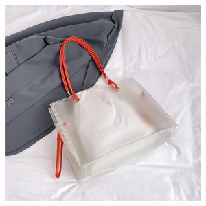 Detail view of transparent frosted PVC tote bag with vibrant orange handles and inner pouch