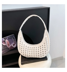Detail der weißen Hobo-Tasche mit silbernen Nieten auf schwarzen Büchern platziert