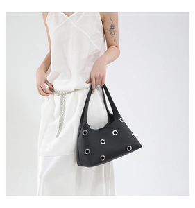 Detail of black lychee grain leather underarm bag with oversized silver metal eyelets