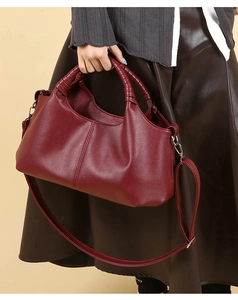 Close-up of burgundy lychee grain leather handbag with braided handles and silver hardware