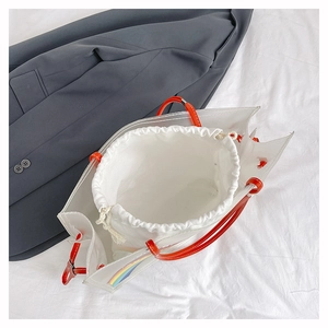 Detail of transparent beach bag with rainbow motif and orange leather handle structure