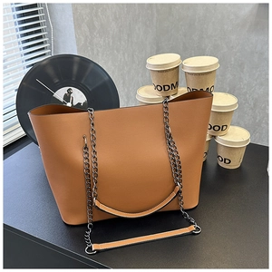 Detail view of large brown leather tote bag with metal chain and leather shoulder strap