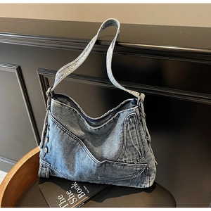 Detailed view of washed blue denim tote showing vintage textures and metal buckle accents