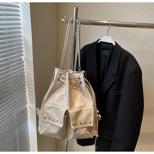 Detail of cream bucket bag with silver studs and metal chain strap in natural light