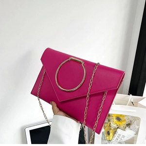 Détail d'une pochette enveloppe magenta avec grand anneau doré et chaîne métallique