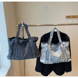 Detail of vintage denim tote bags in dark grey and light blue wash on a metal rack