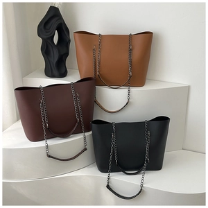 Detail view of tote bags in brown, red, and black with metal chain straps on display