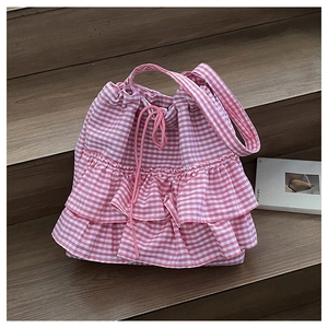 Detail of pink checkered drawstring tote bag with ruffles on wooden stairs
