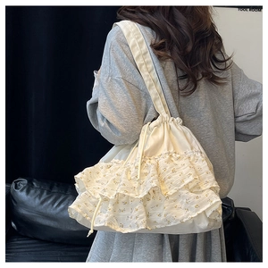 Detalle del bolso tote con volantes florales en lona blanco roto y asa ancha
