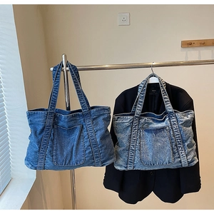 Detailed view of large denim tote bags in dark and light blue wash on metal hangers