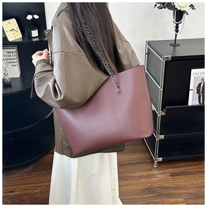Detail of burgundy leather tote bag featuring a silver metal chain and leather strap