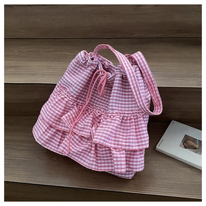 Detail of pink and white checkered ruffled canvas tote bag on a wooden staircase