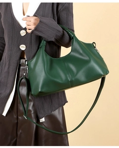 Detail of dark green pebbled leather tote featuring a unique woven handle and shoulder strap