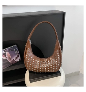 Detailansicht der braunen Hobo-Tasche mit silbernen Nieten auf weißem Hocker