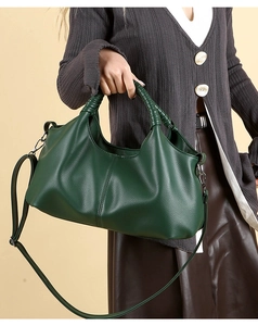 Detail of forest green lychee grain leather tote with woven handles and long strap