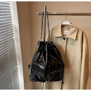 Detailed view of a black drawstring bucket bag with silver studs and chain shoulder strap