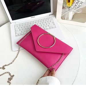 Détail de la pochette enveloppe fuchsia avec grande boucle dorée et bandoulière chaîne
