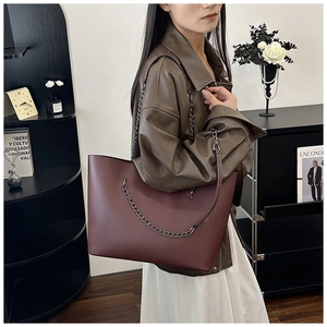 Detail of burgundy leather tote bag with metal chain strap and modern vintage styling