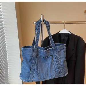 Detailed view of dark blue denim tote bag with front pocket and washed texture finish