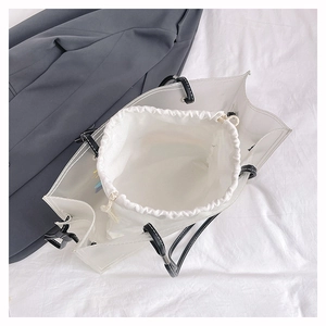 Detail of transparent PVC beach bag with white canvas drawstring liner and black handles