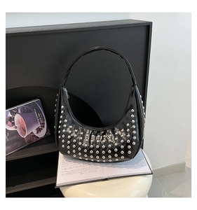 Details einer schwarzen Punk-Hobo-Tasche mit silbernen Nieten auf einem weißen Hocker