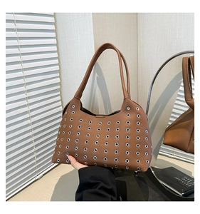 Detail of brown faux leather shoulder bag featuring silver metal eyelet rivet accents