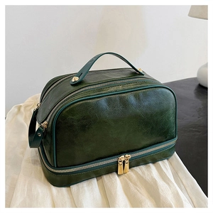 Detail view of dark green retro leather toiletry bag with golden dual zippers and top handle