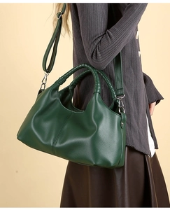 Detail of green leather handbag with woven handle and detachable silver metal buckle strap