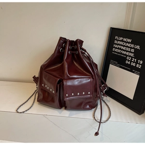 Detailed view of burgundy bucket bag featuring silver studs and chain strap
