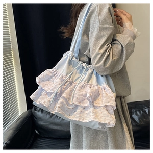 Primer plano del bolso tote azul claro con volantes florales de gasa y correas