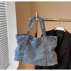 Detailed macro view of high-capacity acid wash denim tote bag with reinforced straps