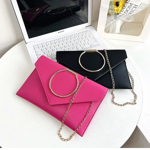 Détail de pochettes enveloppes avec anneaux dorés et chaînes en fuchsia et noir élégant