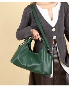 Detail of dark green leather tote with dual handles and long shoulder strap for women