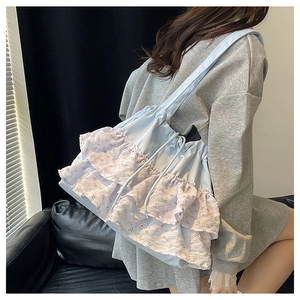Detalle del bolso tote azul claro con volantes florales y textura de tela suave