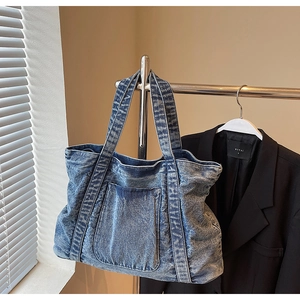 Close-up of vintage washed blue denim tote bag with functional front pocket and texture