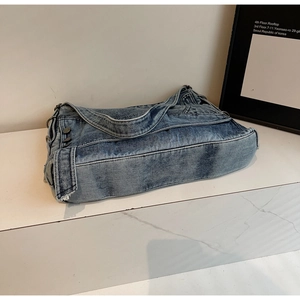 Detailed view of denim tote bag showing functional side pocket and metal button accents