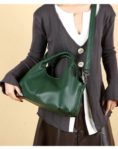 Detail of dark green hobo bag with pebble leather texture and braided top handle